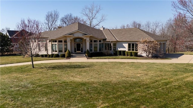view of front facade with stucco siding, a chimney, concrete driveway, and a front yard