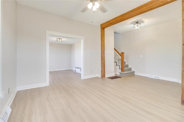 unfurnished living room with light wood-style floors, baseboards, stairs, and visible vents