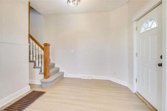 foyer with light wood-style floors, visible vents, stairway, and baseboards