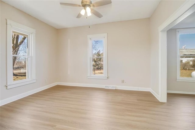 spare room featuring light wood-style floors, plenty of natural light, visible vents, and baseboards