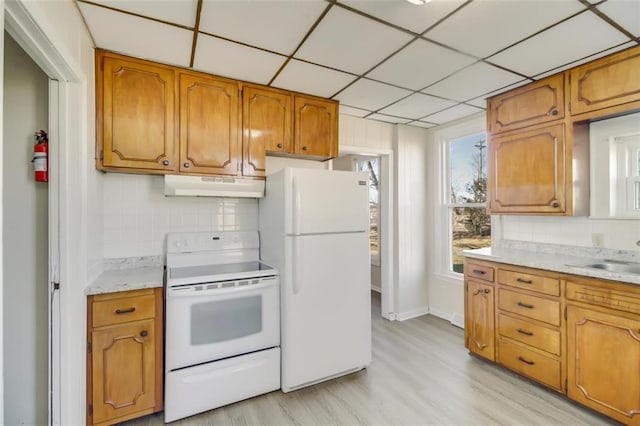 kitchen featuring white appliances, under cabinet range hood, brown cabinets, and decorative backsplash