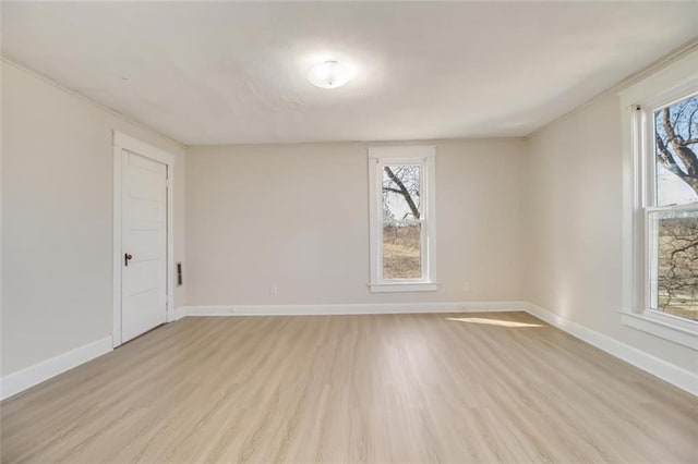 spare room with baseboards, light wood-style flooring, and a healthy amount of sunlight