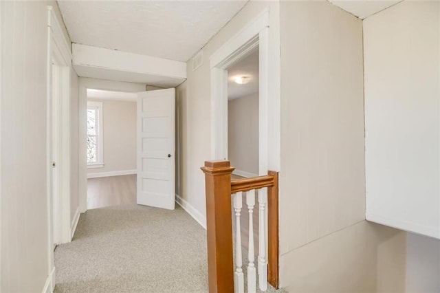 corridor with carpet floors, baseboards, and an upstairs landing