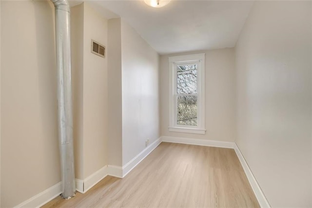 spare room with light wood finished floors, visible vents, and baseboards