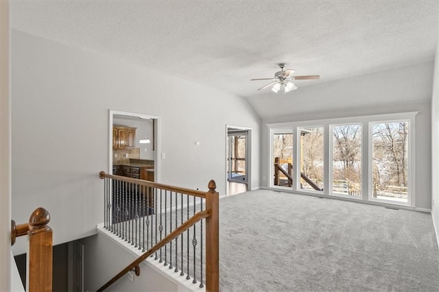 interior space with lofted ceiling, carpet floors, a textured ceiling, and ceiling fan