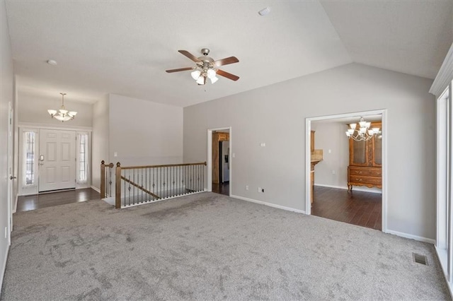 spare room featuring baseboards, visible vents, lofted ceiling, dark colored carpet, and ceiling fan with notable chandelier