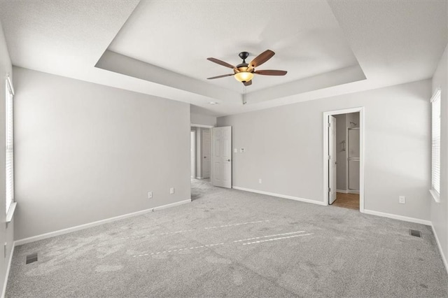 unfurnished bedroom featuring a raised ceiling, visible vents, and baseboards