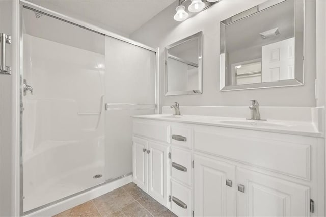 full bathroom with double vanity, a stall shower, a sink, and tile patterned floors