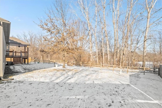 yard layered in snow featuring stairway and fence