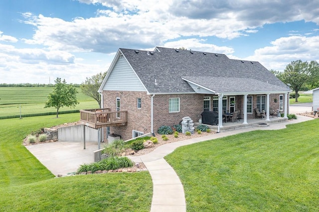 22330 Mclouth Rd, Mclouth, KS 66054 - rear view of house featuring roof with shingles, brick siding, a patio, a lawn, and a wooden deck