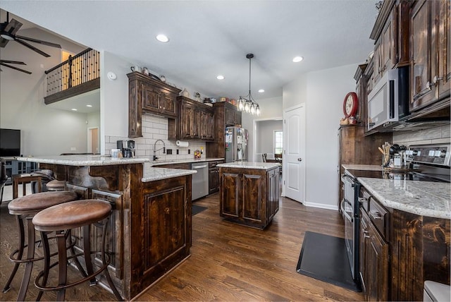 22330 Mclouth Rd, Mclouth, KS 66054 - kitchen featuring ceiling fan, stainless steel appliances, dark wood-type flooring, dark brown cabinets, and a center island
