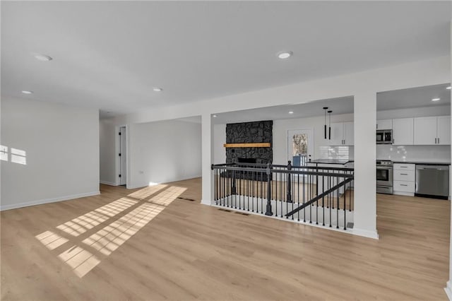 empty room with a fireplace and light wood-type flooring