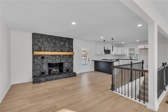 living room featuring a fireplace, light hardwood / wood-style flooring, and sink