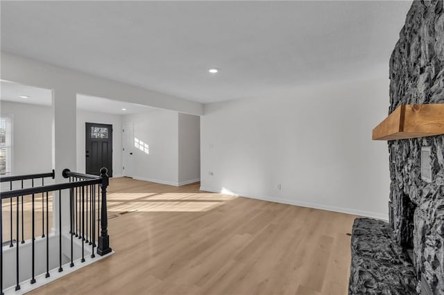 living room featuring a stone fireplace and light hardwood / wood-style floors