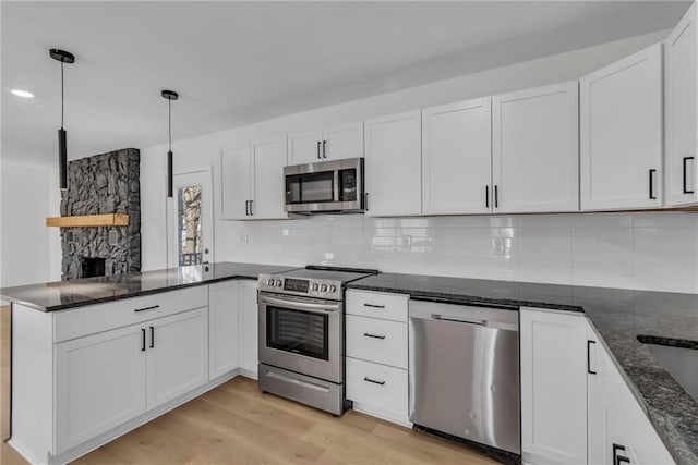 kitchen featuring pendant lighting, tasteful backsplash, white cabinets, stainless steel appliances, and light wood-type flooring