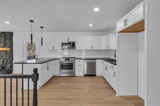 kitchen with pendant lighting, appliances with stainless steel finishes, kitchen peninsula, and white cabinets