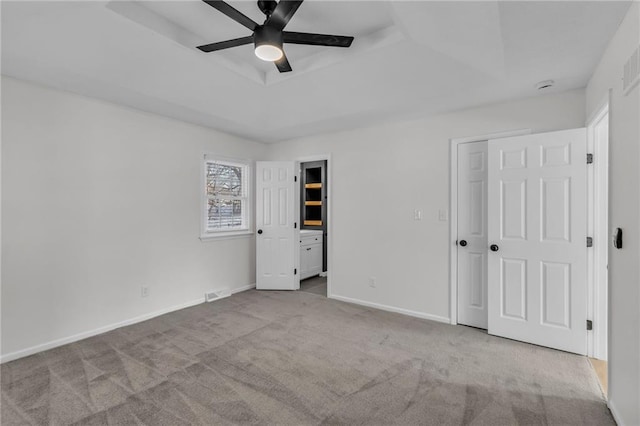 unfurnished bedroom featuring ceiling fan, light colored carpet, and a raised ceiling