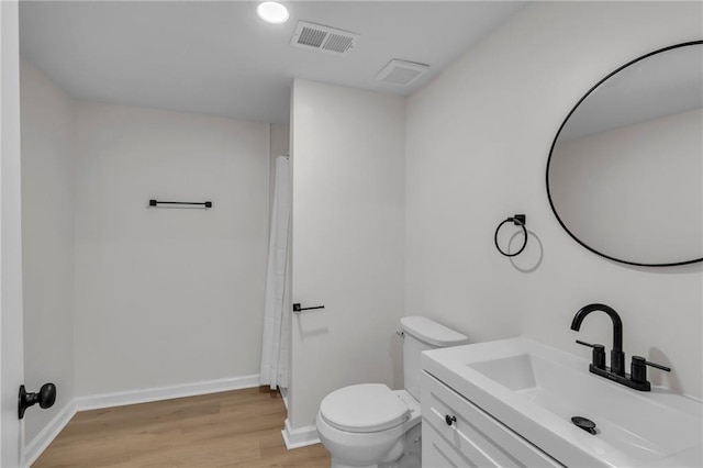 bathroom with hardwood / wood-style flooring, vanity, toilet, and curtained shower