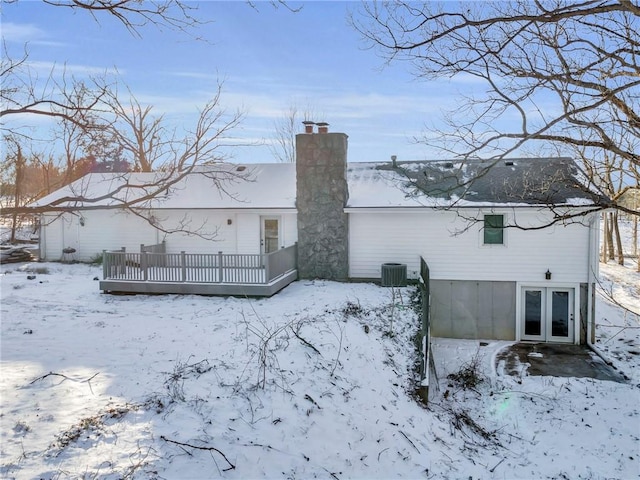 snow covered back of property with cooling unit and a deck