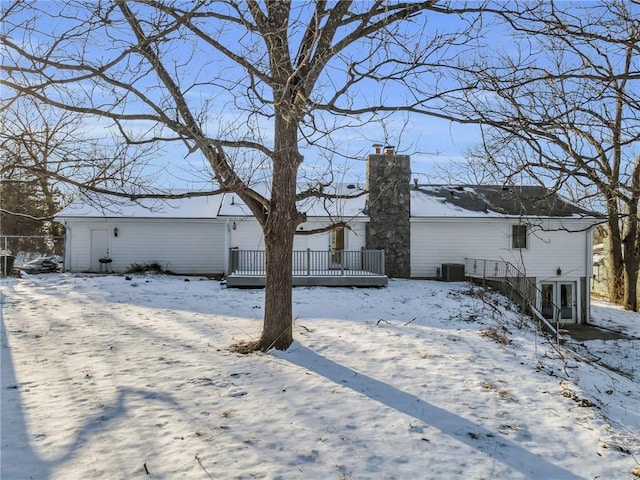 snow covered property with central AC unit and a deck