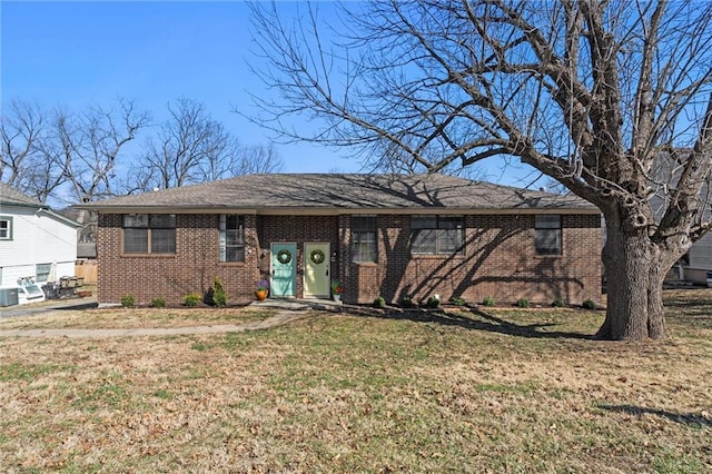 ranch-style house featuring brick siding, central AC unit, and a front lawn