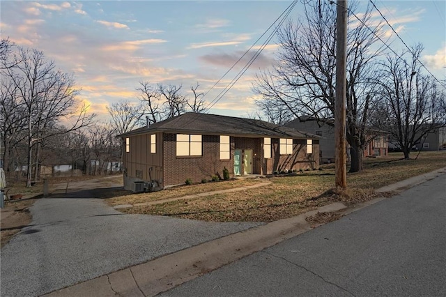 view of front of home with aphalt driveway, brick siding, board and batten siding, and cooling unit