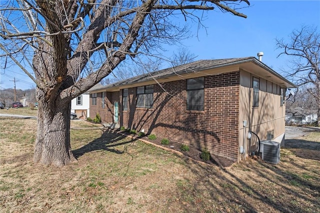 view of property exterior featuring brick siding, central AC unit, and a lawn