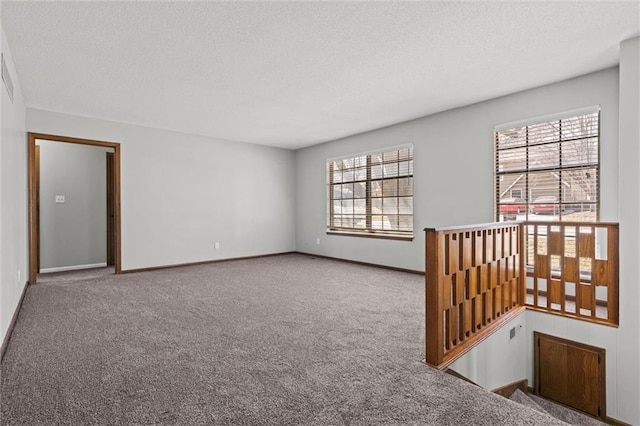 unfurnished room with baseboards, carpet floors, and a textured ceiling