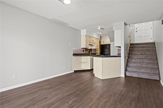 kitchen with dark countertops, freestanding refrigerator, baseboards, and dark wood-style flooring