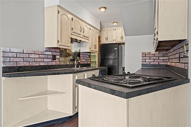 kitchen with dark countertops, backsplash, electric cooktop, a peninsula, and freestanding refrigerator