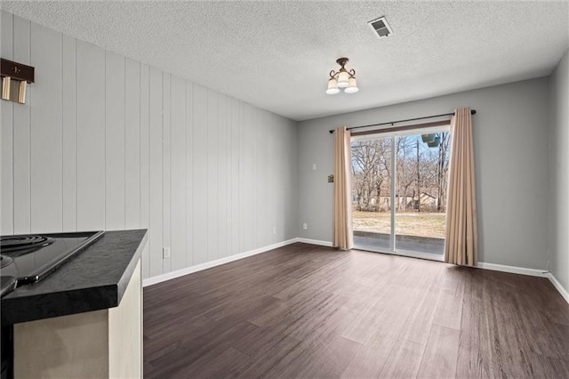 unfurnished living room with visible vents, baseboards, dark wood-type flooring, and a textured ceiling