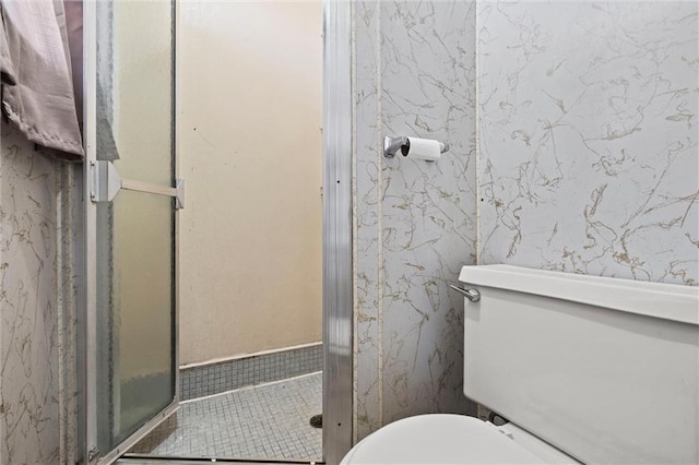 full bathroom featuring wallpapered walls, toilet, and a stall shower