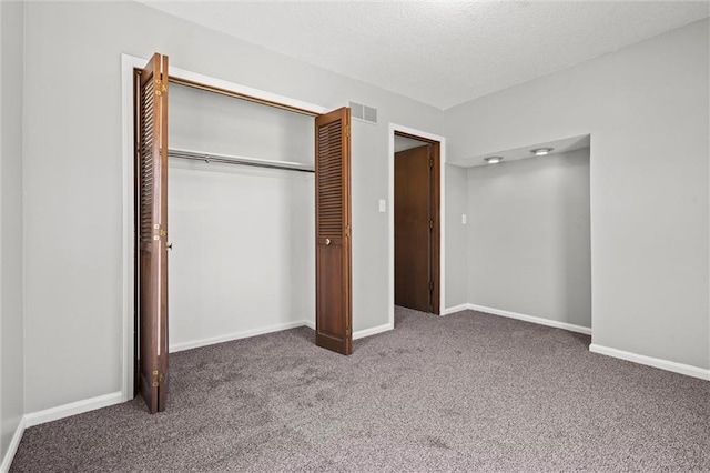 unfurnished bedroom featuring visible vents, baseboards, carpet floors, a closet, and a textured ceiling