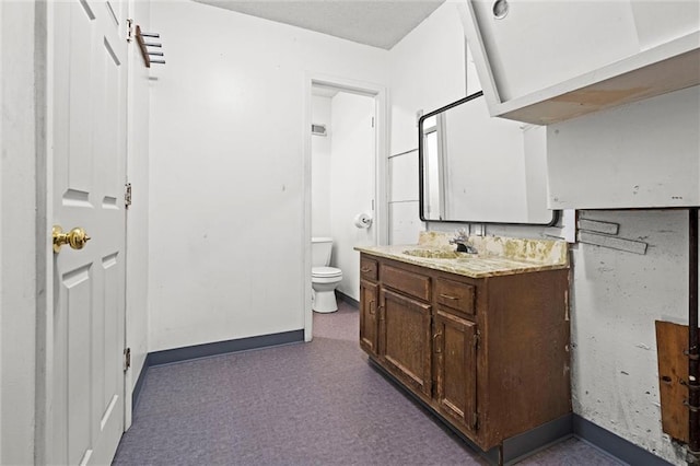 bathroom with vanity, toilet, baseboards, and carpet floors