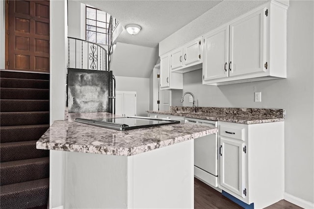 kitchen featuring dishwashing machine, white cabinetry, and freestanding refrigerator