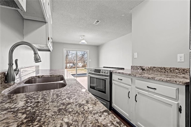 kitchen featuring visible vents, stone counters, stainless steel range with electric cooktop, white cabinets, and a sink