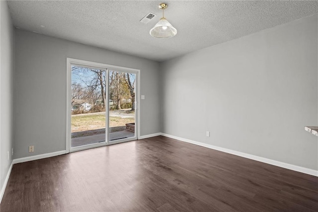 empty room with visible vents, baseboards, dark wood-type flooring, and a textured ceiling