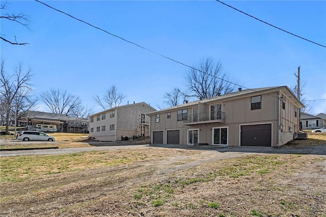 rear view of property featuring central air condition unit, an attached garage, and driveway