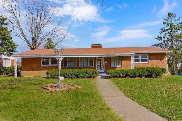 ranch-style home with brick siding, a chimney, and a front lawn