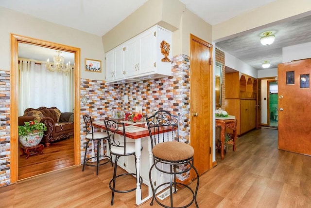 kitchen with white cabinetry, an inviting chandelier, plenty of natural light, and light wood-type flooring