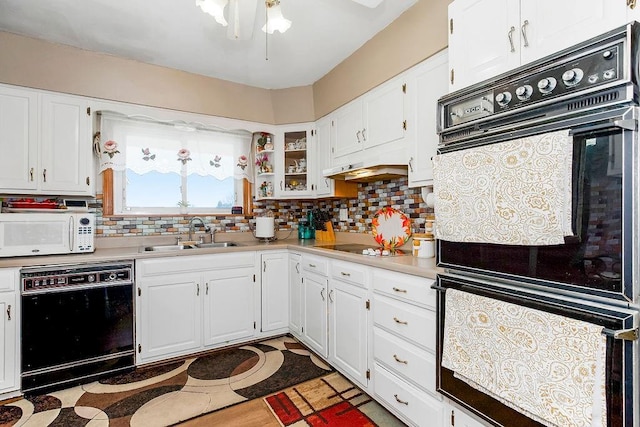 kitchen with backsplash, light countertops, white cabinets, black appliances, and a sink