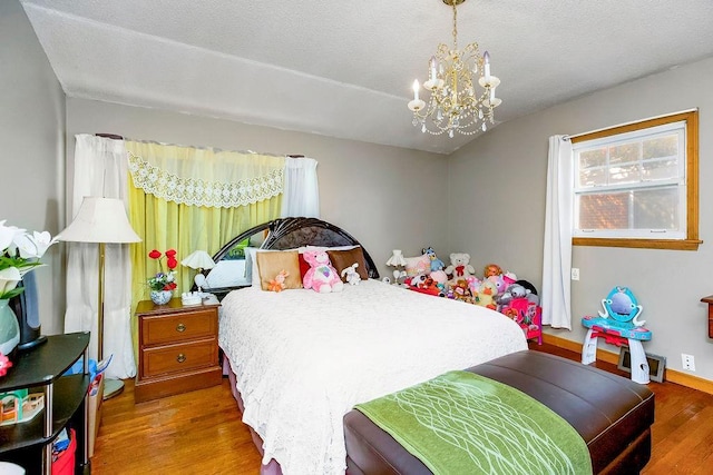 bedroom with a notable chandelier, wood finished floors, and a textured ceiling