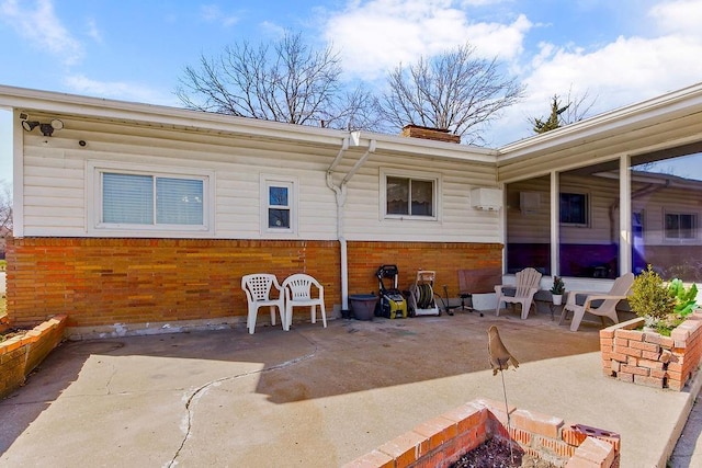 rear view of house with a wall mounted air conditioner and a patio