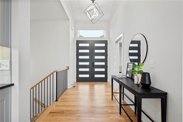 foyer entrance with french doors, an inviting chandelier, and light hardwood / wood-style floors