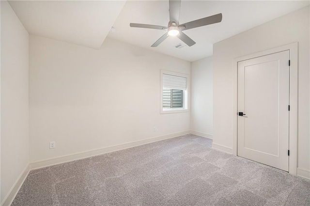 carpeted spare room featuring baseboards, visible vents, and ceiling fan