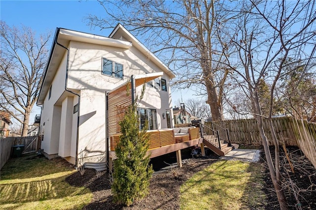 view of home's exterior featuring a wooden deck, a yard, a fenced backyard, and stucco siding