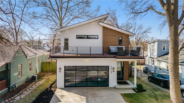 modern home featuring fence, stucco siding, driveway, a balcony, and an attached garage