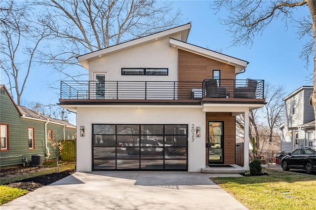 modern home with a balcony, stucco siding, concrete driveway, a front lawn, and central air condition unit