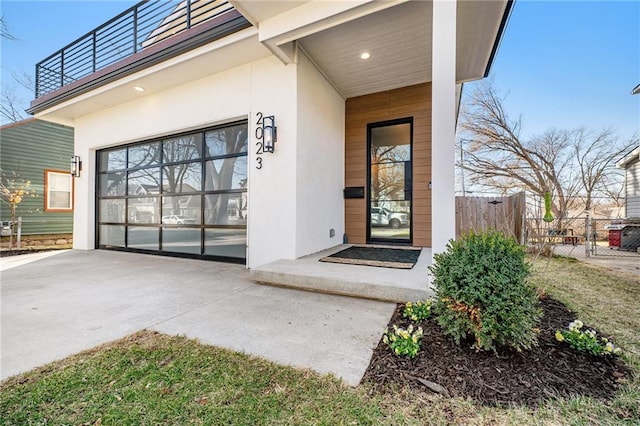 entrance to property featuring stucco siding, a balcony, and fence