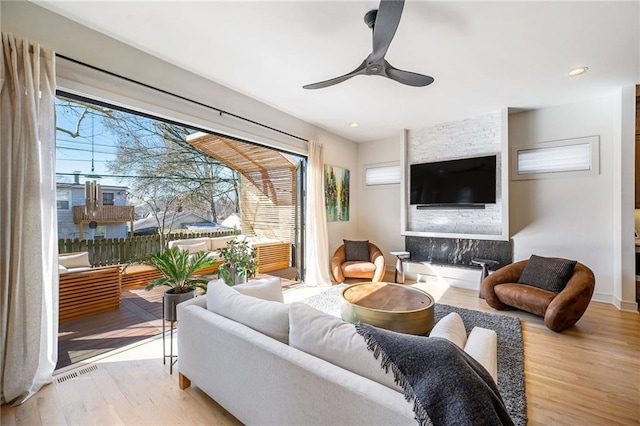 living room featuring a ceiling fan, wood finished floors, a healthy amount of sunlight, and visible vents